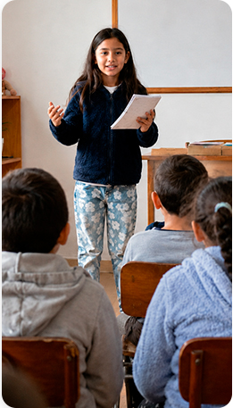 Niña de pie hablando frente a una clase